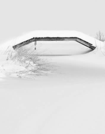 A small bridge over a pond everything covered in white snow